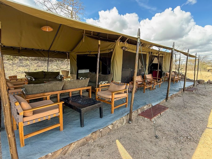 The lounge tent from outside under a blue sky with cumulus clouds, furniture set on a stone terrace